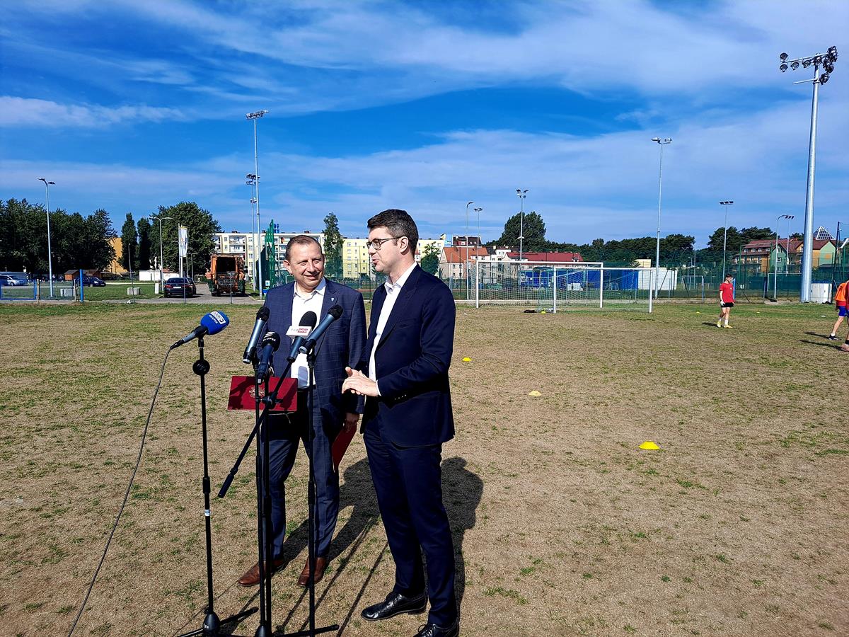 Minister i Burmistrz stoją przy mikrofonach, w tle boisko