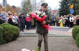 składanie wiązanek kwiatów pod pomnikiem - w tle uczestnicy uroczystości