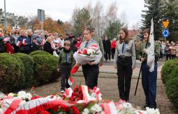 składanie wiązanek kwiatów pod pomnikiem - w tle uczestnicy uroczystości