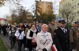 marsz ulicami, uczestnicy rozmawiają, niosą chorągiewki