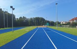 niebieska bieżnia na stadionie lekkoatletycznym, w tle las