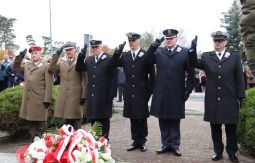 składanie wiązanek kwiatów pod pomnikiem - w tle uczestnicy uroczystości