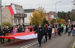 dzieci niosą flagę narodową, w tle uczestnicy