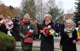 składanie wiązanek kwiatów pod pomnikiem - w tle uczestnicy uroczystości