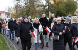 marsz ulicami, uczestnicy rozmawiają, niosą chorągiewki