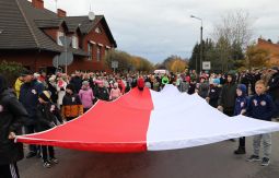 dzieci niosą flagę narodową, w tle uczestnicy