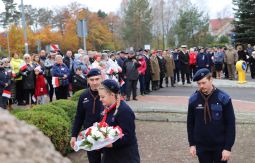 składanie wiązanek kwiatów pod pomnikiem - w tle uczestnicy uroczystości