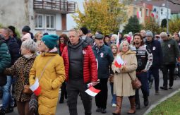 marsz ulicami, uczestnicy rozmawiają, niosą chorągiewki