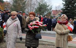 składanie wiązanek kwiatów pod pomnikiem - w tle uczestnicy uroczystości