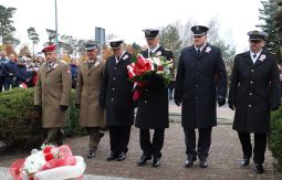 składanie wiązanek kwiatów pod pomnikiem - w tle uczestnicy uroczystości