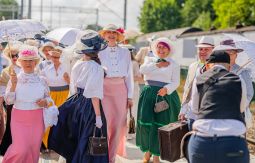 Letnicy w strojach historycznych, trzymają walizki,parasolki