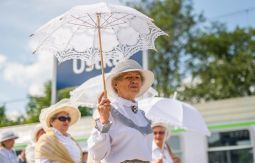 Kobieta w stroju historycznym z koronkową parasolką, w tle napis Ustka