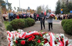 składanie wiązanek kwiatów pod pomnikiem - w tle uczestnicy uroczystości