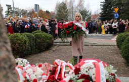 składanie wiązanek kwiatów pod pomnikiem - w tle uczestnicy uroczystości