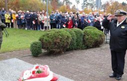 składanie wiązanek kwiatów pod pomnikiem - w tle uczestnicy uroczystości