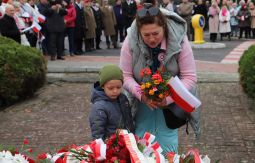 składanie wiązanek kwiatów pod pomnikiem - w tle uczestnicy uroczystości