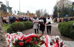 składanie wiązanek kwiatów pod pomnikiem - w tle uczestnicy uroczystości