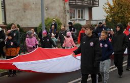 dzieci niosą flagę narodową, w tle uczestnicy