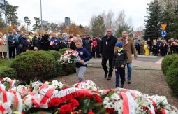 składanie wiązanek kwiatów pod pomnikiem - w tle uczestnicy uroczystości