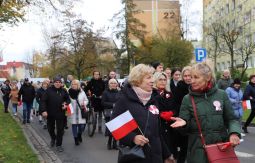 marsz ulicami, uczestnicy rozmawiają, niosą chorągiewki