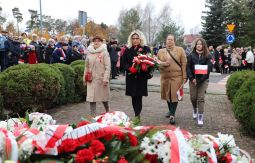 składanie wiązanek kwiatów pod pomnikiem - w tle uczestnicy uroczystości