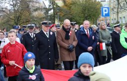 dzieci niosą flagę, w tle uczestnicy marszu