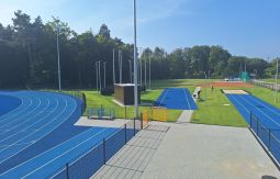 niebieska bieżnia na stadionie lekkoatletycznym, w tle las