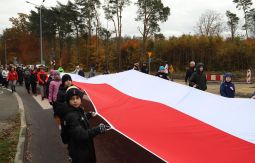 dzieci niosą flagę narodową, w tle uczestnicy